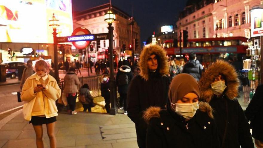 Varias personas, con y sin mascarilla, pasean por el centro de Londres.