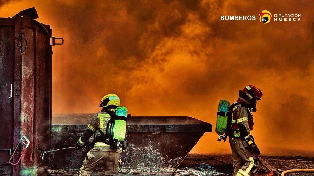 Dos Bomberos de la DPH en medio de las llamas del iniciado este viernes en una planta de reciclado de Fraga.