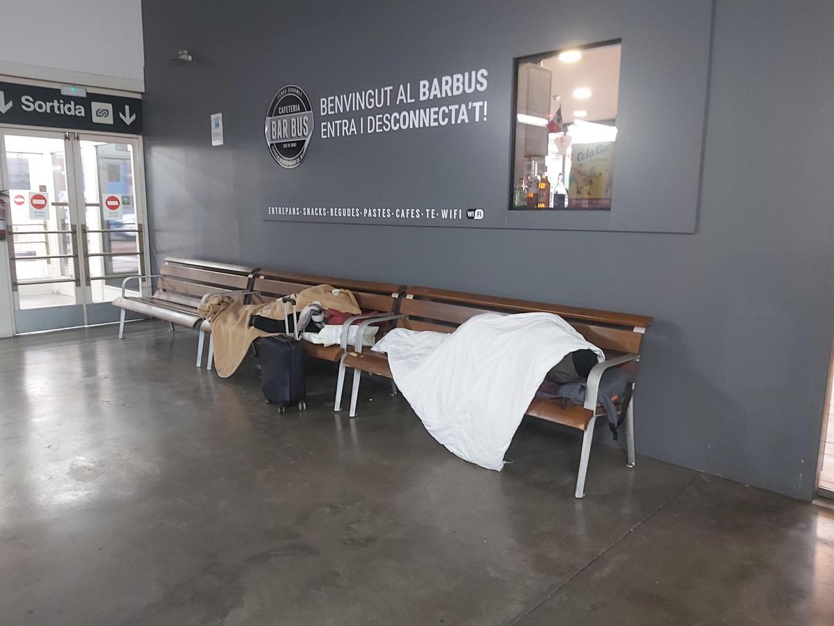 Imatge de dues persones dormint a l'estació de busos de Manresa