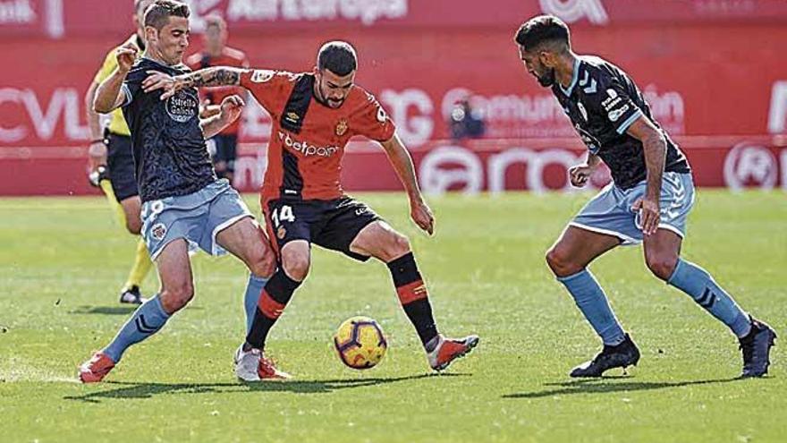 Dani RodrÃ­guez controla el balÃ³n entre dos rivales.