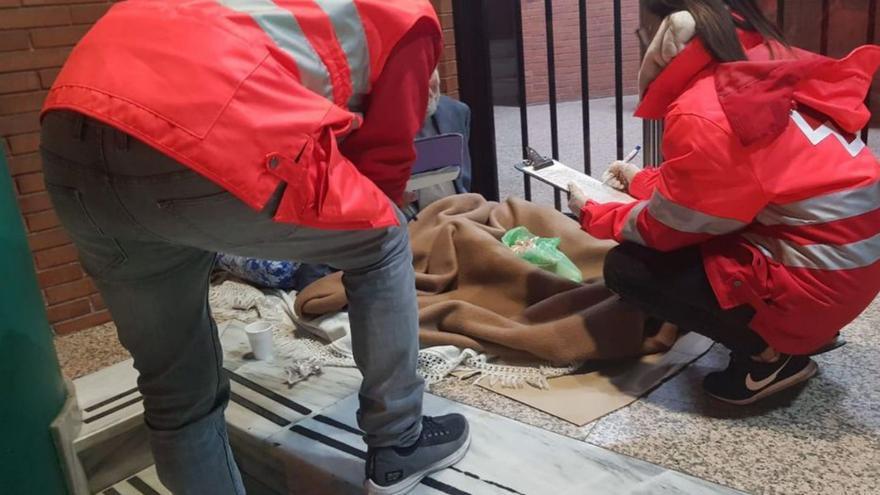 Trabajadores de Cruz Roja atendiendo a un hombre que vive en la calle.