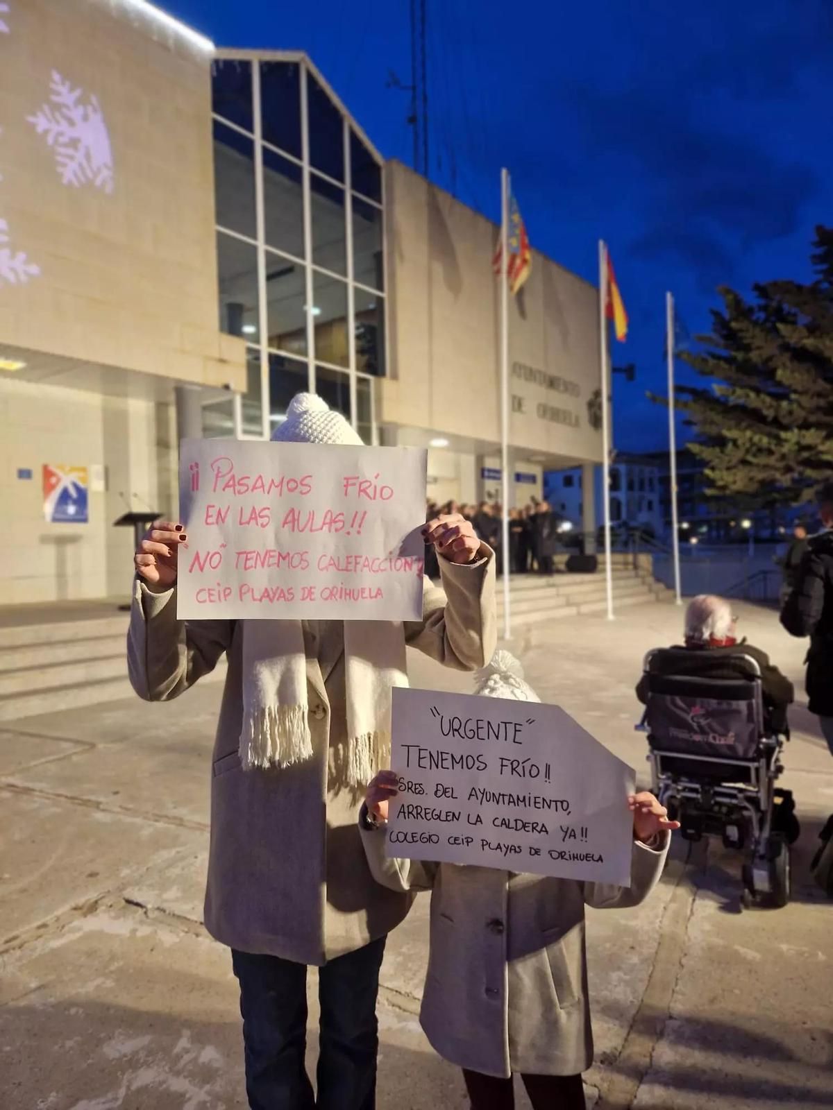 Carteles de padres y alumnos frente a la sede del Ayuntamiento de Orihuela Costa que reclaman calefacción en el colegio Playas de Orihuela