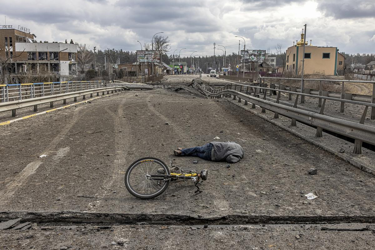 El cadáver de un hombre yace junto a una bicicleta en medio de un puente destruido en la ciudad de Irpin, el 7 de marzo de 2022.