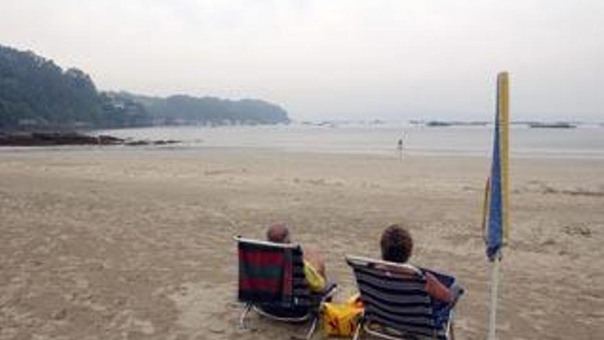 Bañistas en la playa un día nublado de verano.