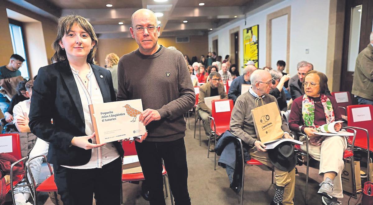 Claudia Elena Menéndez y David Guardo sostienen un ejemplar del Pequeñu Atles Lingüístico d'Asturies