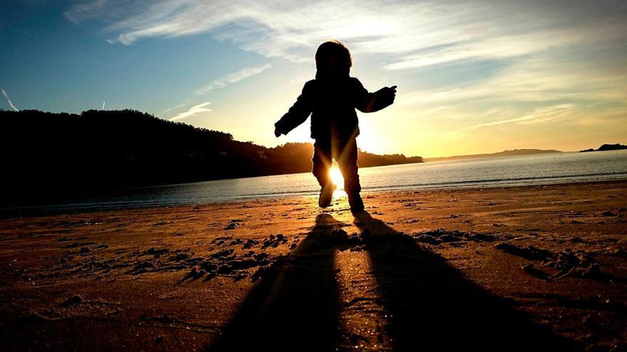 Un niño, abrigado, juega en una playa de Galicia // Cabalar