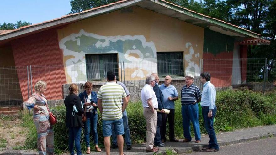 Vecinos y miembros del PP local y regional, ayer, ante uno de los chalés abandonados de Perlora.