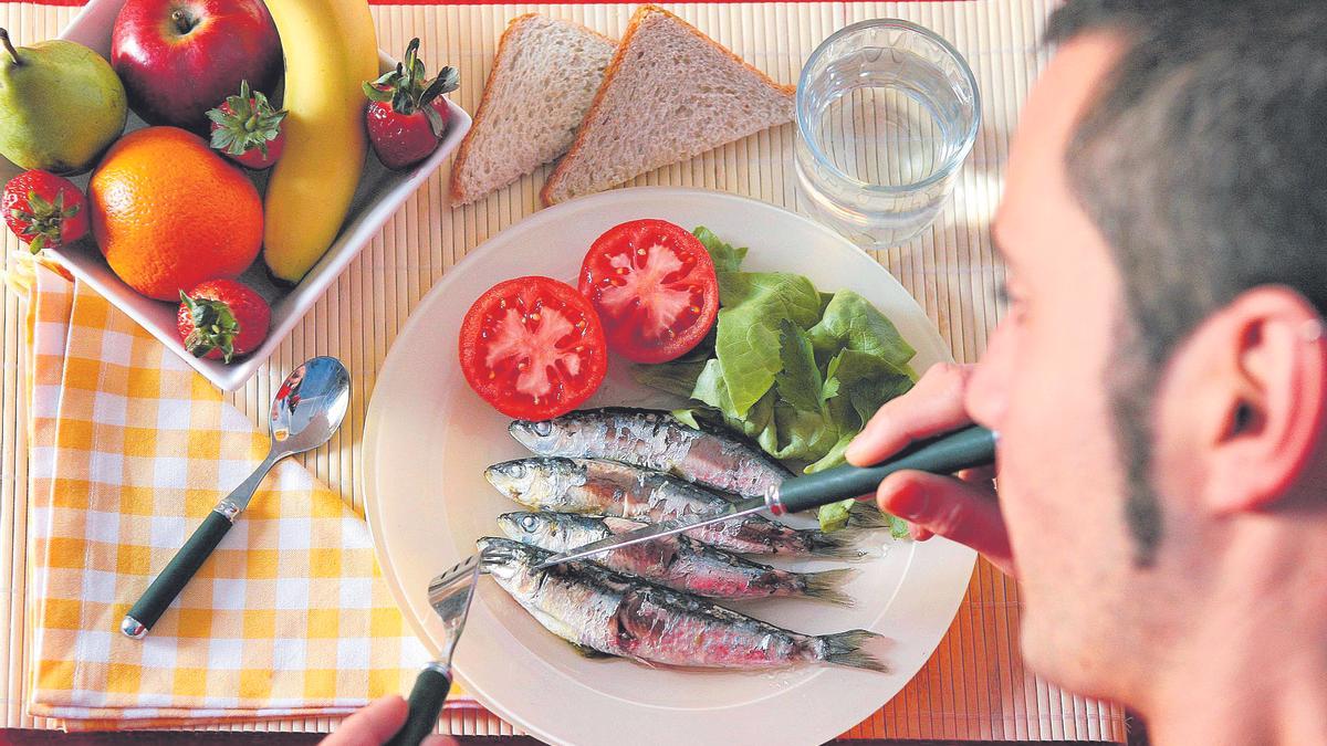 Un joven se dispone a comer un plato saludable compuesto por pescado azul y verduras.