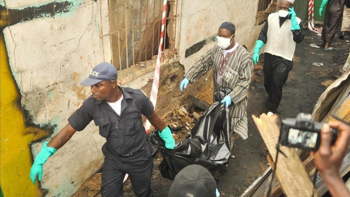 Personal de los servicios de rescate desalojan un cadáver del lugar del siniestro, en Monrovia.