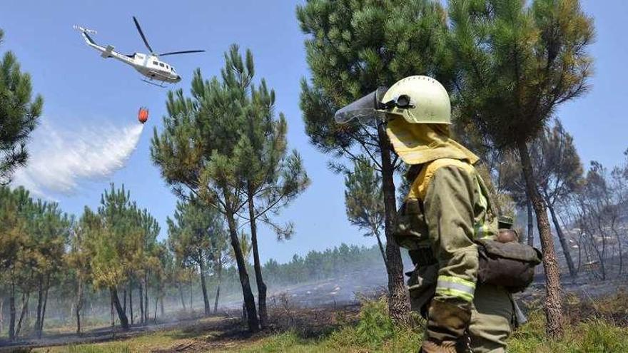 Uno de los dos helicópteros echa agua sobre la zona afectada en Santo André de Xeve. // Gustavo Santos