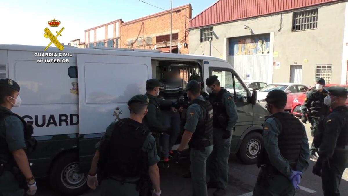 Los guardias civiles custodian a uno de los detenidos en la operación.
