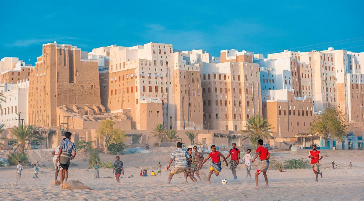 Un grupo de jóvenes juega a fútbol en una ciudad de Yemen
