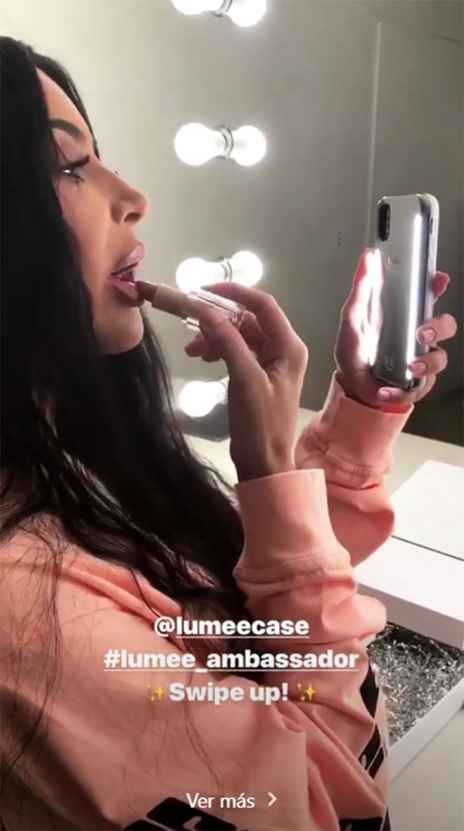 Kim Kardashian pintándose los labios en el espejo de su móvil