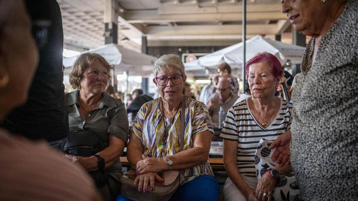 Varias jubiladas descansan en una zona comercial.