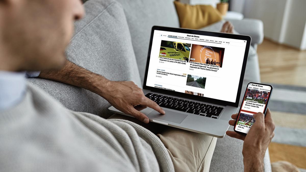 Una persona consultant l’edició digital de Diari de Girona en un ordinador i en un mòbil.