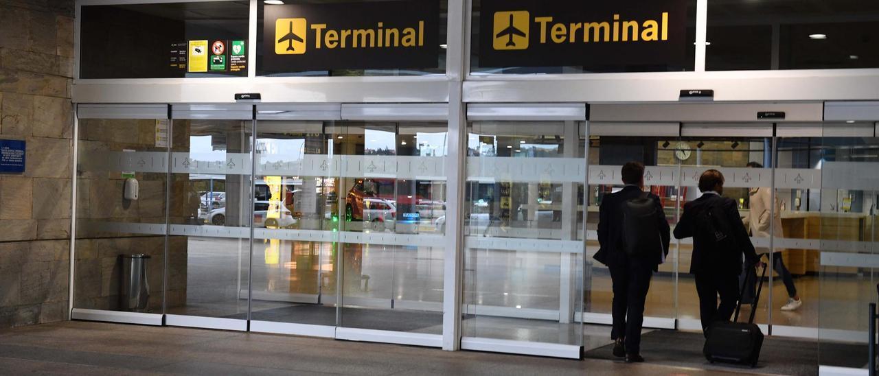 Dos hombres acceden a la terminal del aeropuerto de Alvedro.