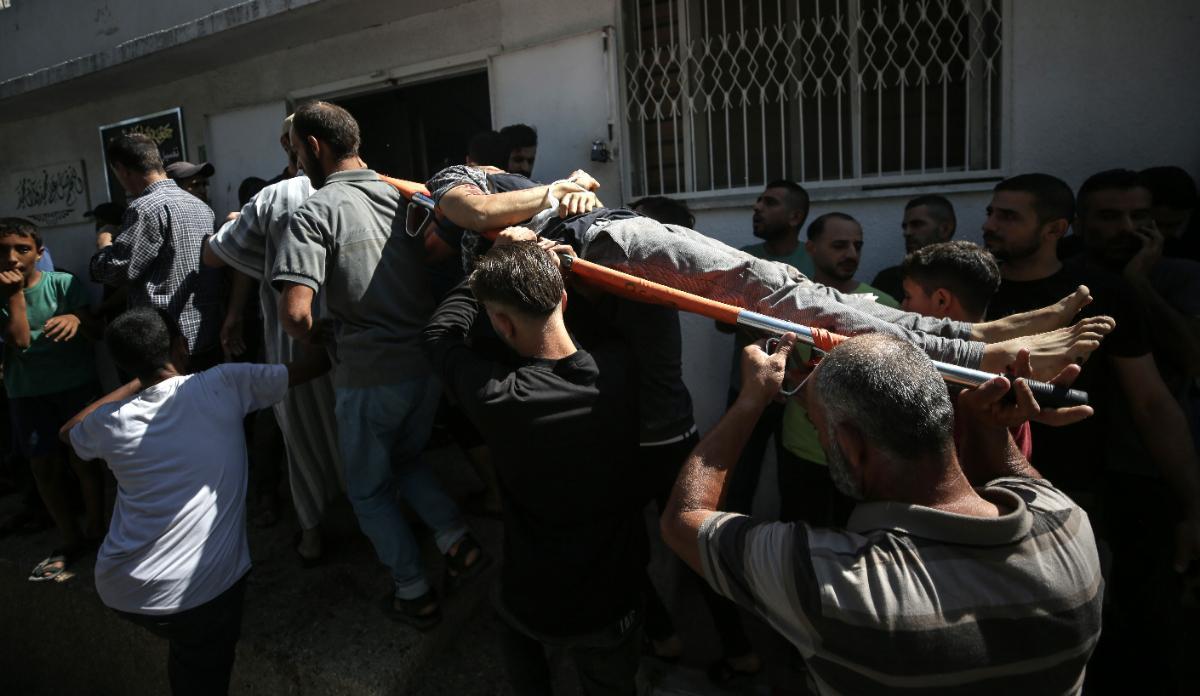 Los palestinos cargan el cuerpo de un combatiente muerto durante el asalto a los asentamientos israelíes por parte de militantes de la milicia Ezz Al-Din Al Qassam, el ala militar del movimiento Hamas, en el hospital Al-Shifa en la ciudad de Gaza, el 7 de octubre de 2023.