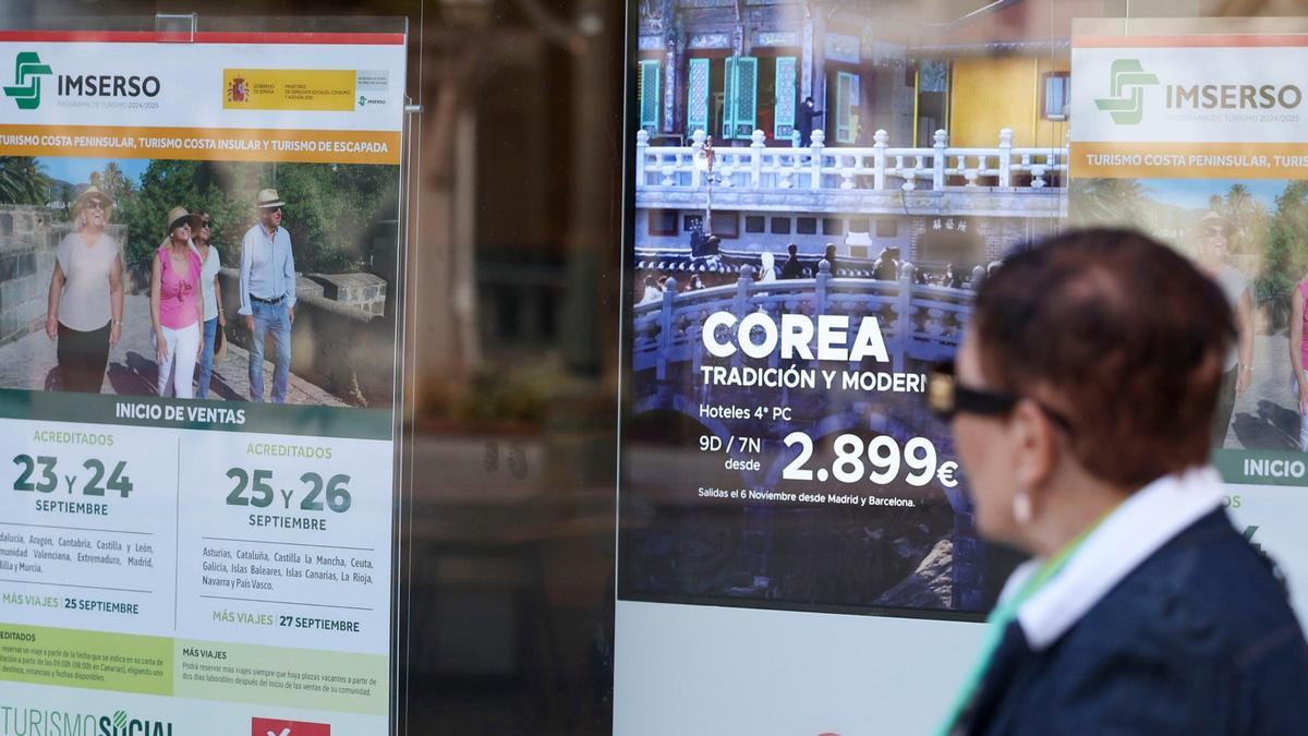 Una jubilada pasa por delante de una agencia donde se anuncian viajes del Imserso.
