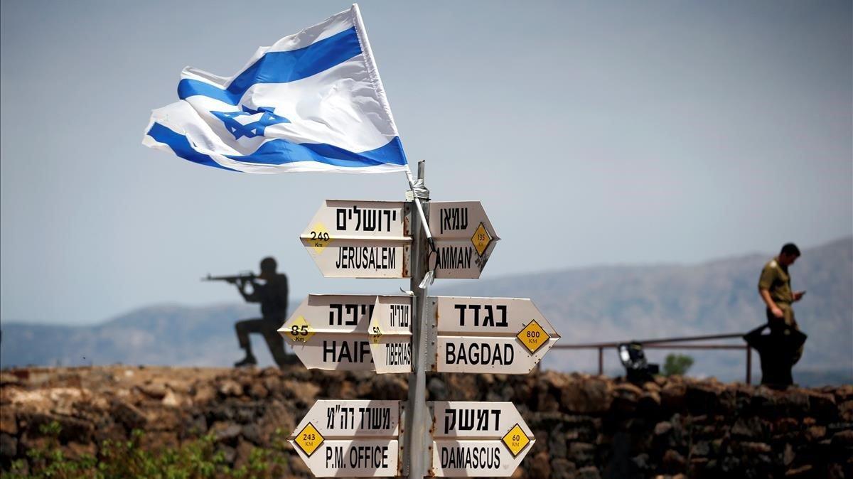 Un soldado israelí se para al lado de los letreros que señalan las distancias a diferentes ciudades en el Monte Bental, un punto de observación en los Altos del Golán ocupados por los israelíes que pasan por alto el lado sirio del Quneitra que cruza Israel.