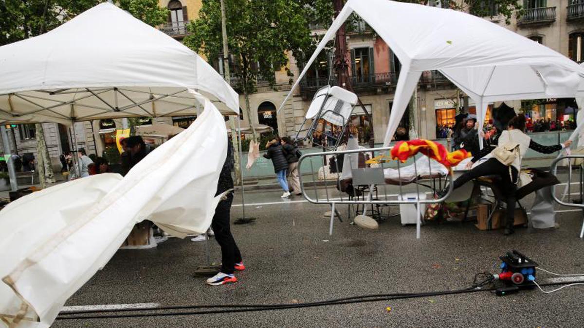 Diada de Sant Jordi en el Passeig de Gràcia, libros, rosas, lluvia y viento, desperfectos en la parada de la libreria Tripode