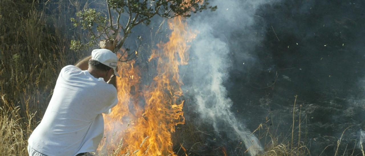 Un hombre intenta apagar el fuego provocado este verano en Bretó