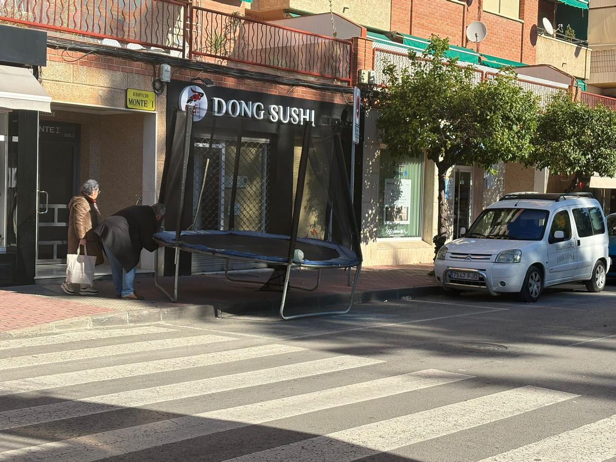 Dos vecinos recogen una cama elástica en la avenida Monteazahar.