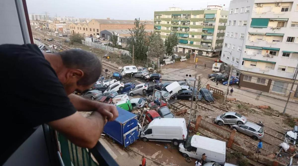 Un vecino observa desde su balcón el desastre tras la dana en el paso a nivel de Alfafar.