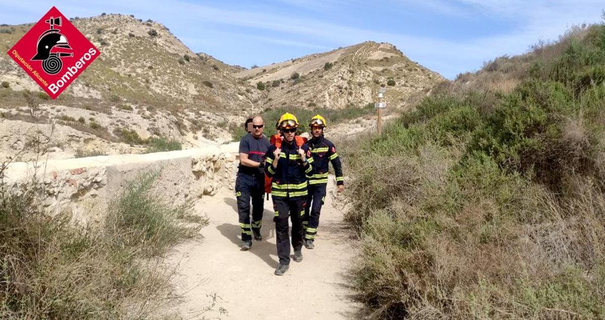 Cuatro bomberos portean a la mujer hasta la ambulancia hoy en las inmediaciones del Pantano de Elche