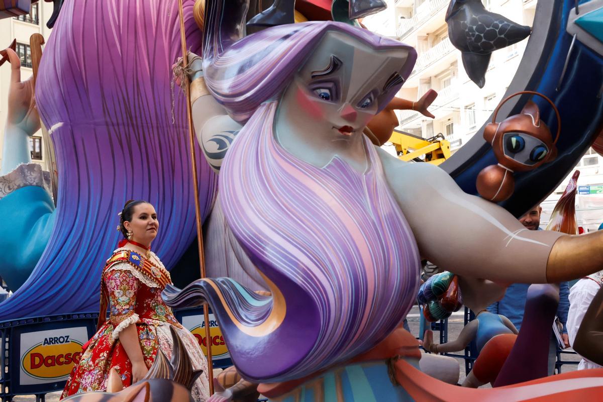 A woman in a traditional dress stands next to a Ninot or giant figure displayed in the streets before being burned during the traditional annual Fallas festival, in Valencia, Spain, March 15, 2024. REUTERS/Eva Manez