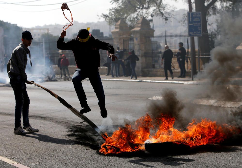 Palestinian demonstrator jumps over a burning ...