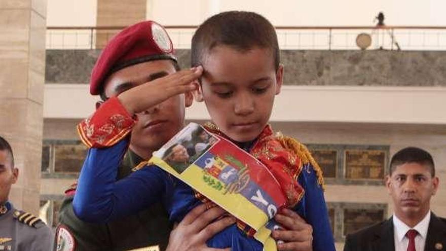 Un niño, disfrazado de Bolívar, saluda ante el féretro. // Efe