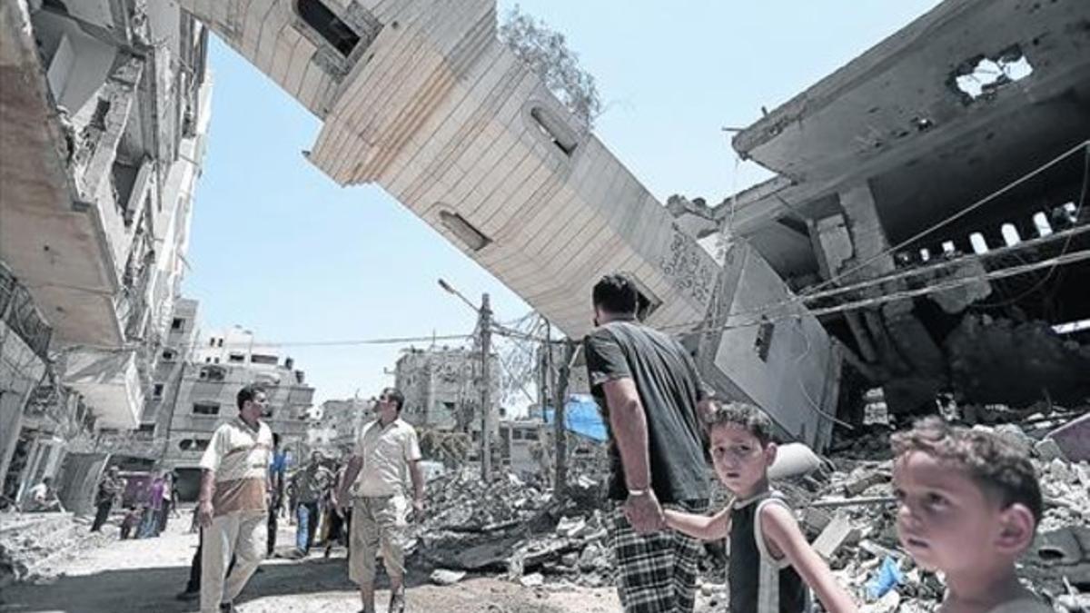 Civiles palestinos inspeccionan los daños en un vecindario de Gaza causados por un bombardeo israelí, ayer.