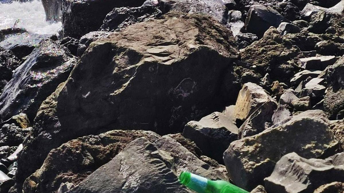 Botella en primer plano entre las rocas de la playa Bocabarranco, Telde. (L)  | RUTH JAÉN-MOLINA