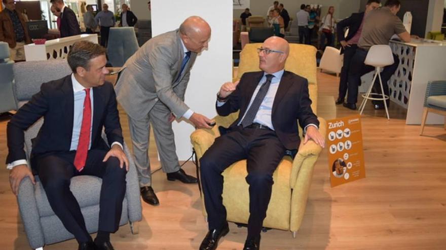 El consejero y el alcalde, en el centro, probando uno de los sillones que se exhiben en la feria.