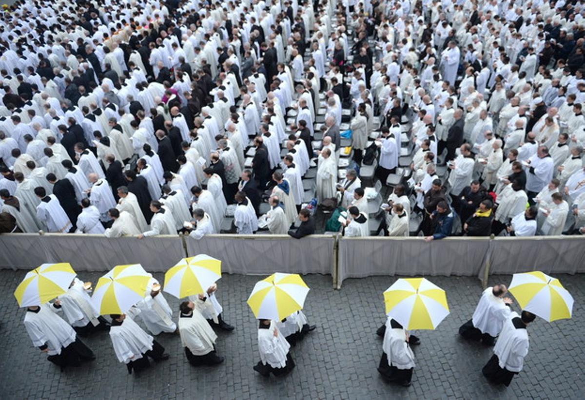 Sacerdotes, con paraguas de los colores del Vaticano, en la Plaza de San Pedro.