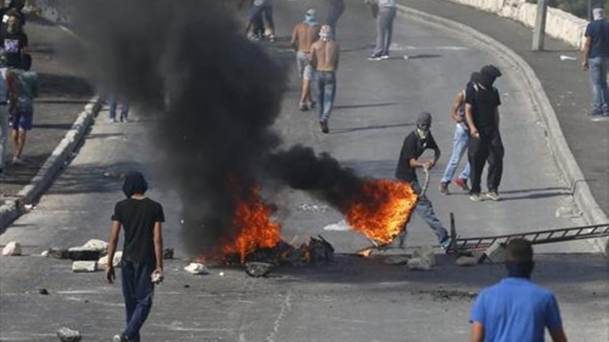 Un palestino arrastra un neumático incendiado, en Jerusalén Este.