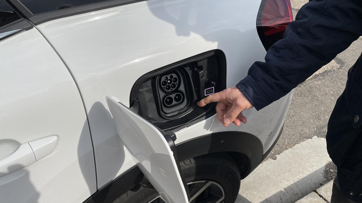 Morón señala el punto en el que se enchufa su coche a la red para recargarlo.