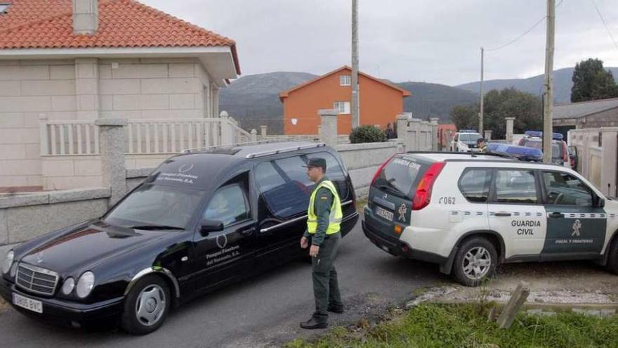 Uno de los coches fúnebres abandona la vivienda donde aparecieron los cuerpos.