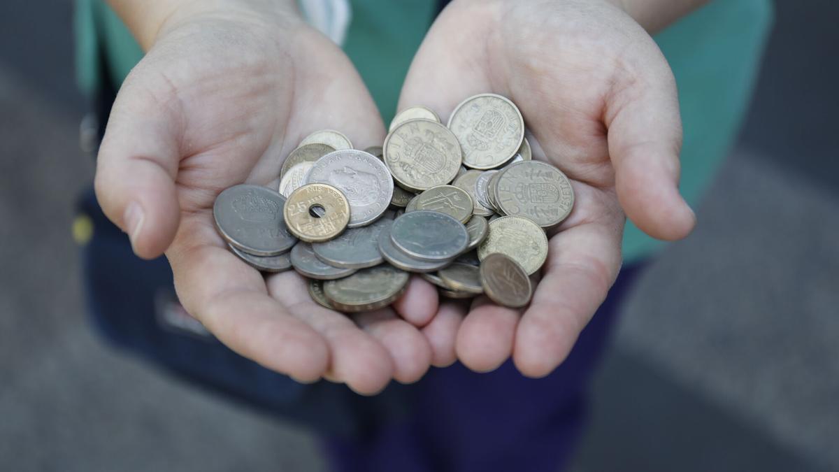 Una persona muestra un puñado de monedas de las antiguas pesetas.