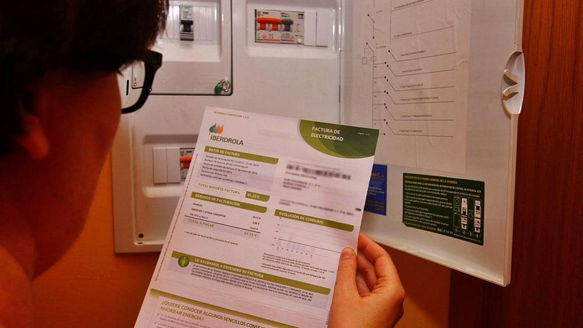 Una dona consulta una factura al costat del seu comptador