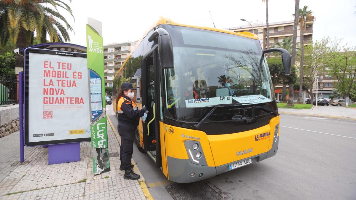 Una voluntaria de Protección Civil reparte mascarillas en la estación de la Marina en Gandia