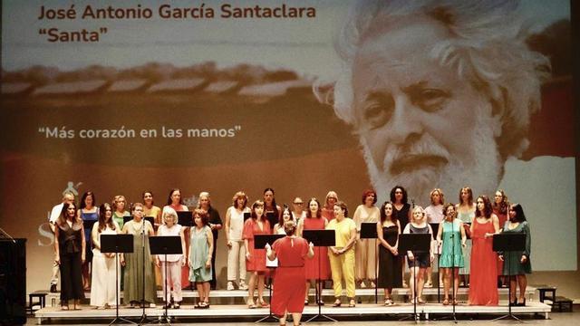 El coro Asturias Gospel Experience, en el escenario con una gran foto de José Antonio García Santaclara al fondo. | MARCOS LEÓN