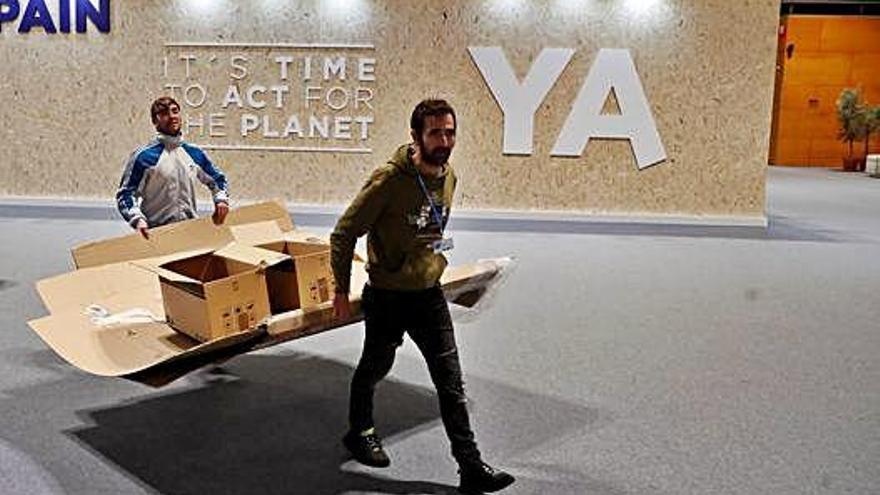 Dos operarios desmontan un &#039;stand&#039; en la Cumbre del Clima de Madrid.