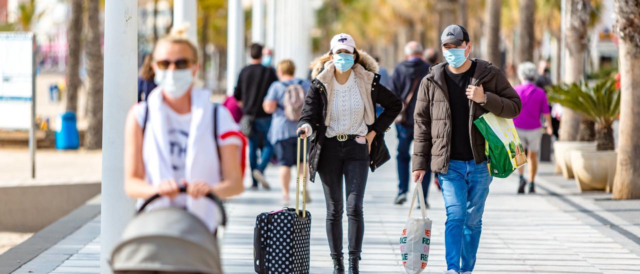 Turistas con maletas en el paseo de la playa de Levante de  Benidorm