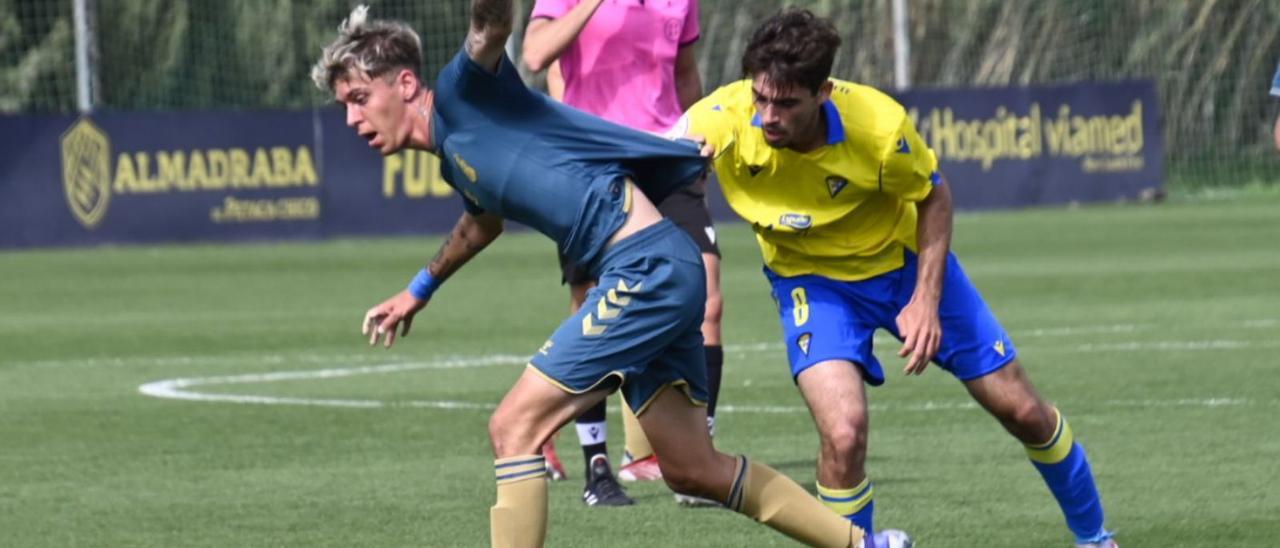 Pol Salvador, agarrado por un jugador del Cádiz B durante el partido de ayer.