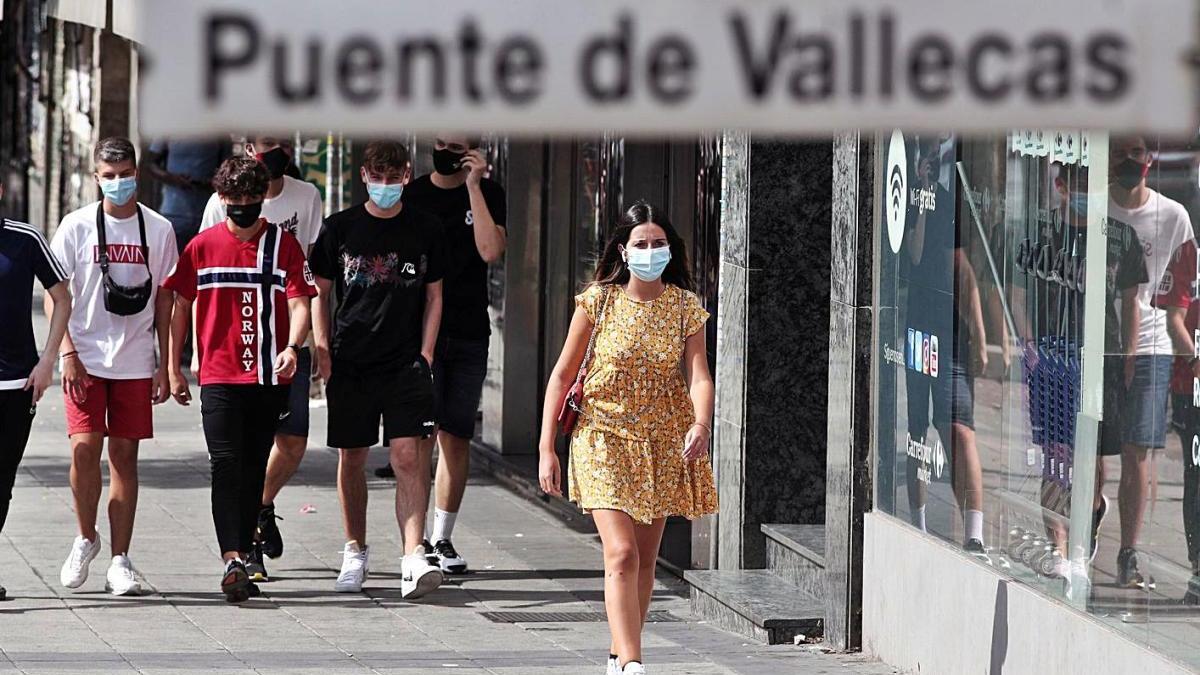 Vecinos caminan ayer con mascarilla al lado del metro de Puente de Vallecas, en Madrid.