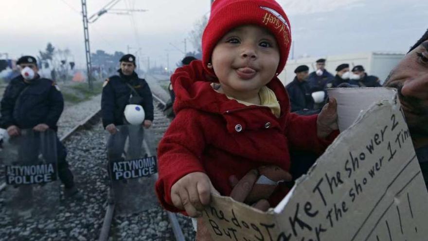 Una niña sostiene un cartel reivindicativo en el campo de Idomeni. // Armando Babani