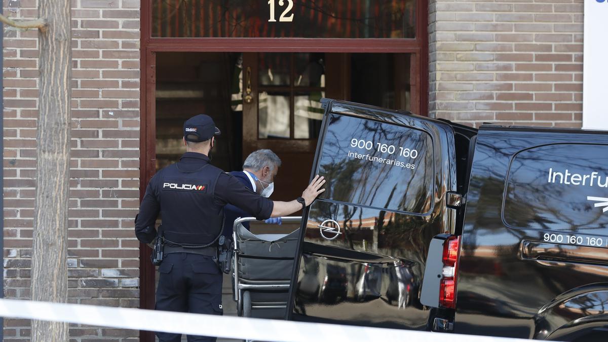 Un empleado de una funeraria junto a un agente de policía, en el edificio de Carabanchel donde, presuntamente, la mujer de 56 años ha asesinado a una de sus vecinas.