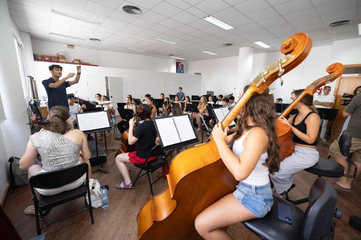 La orquesta ensaya con los contrabajos en primer plano.