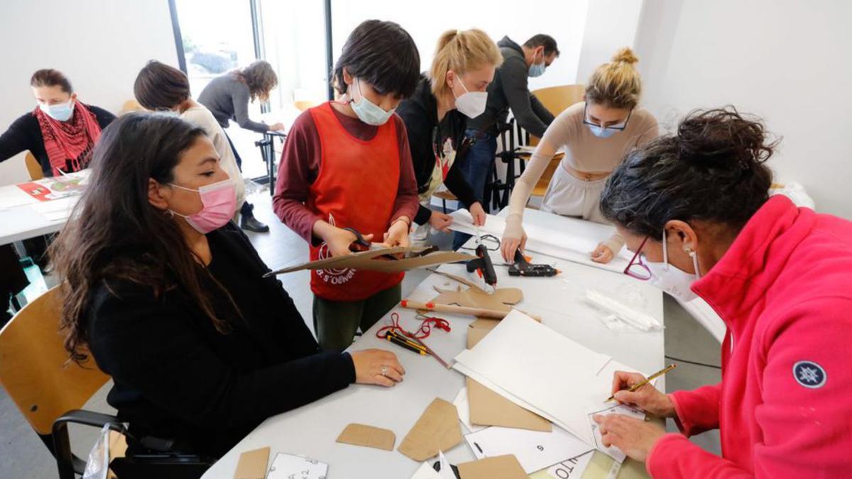 Algunos de los asistentes dibujan y recortan cartulina.  | J.A. RIERA